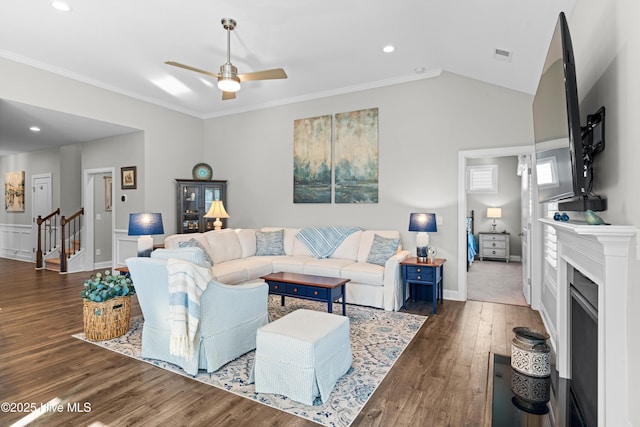 living room with ceiling fan, dark wood-type flooring, ornamental molding, and vaulted ceiling