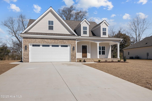 view of front of house featuring covered porch, a garage, brick siding, driveway, and roof with shingles