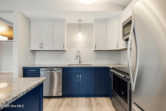 11 White Ln, Oak Island, NC 28465 - kitchen featuring appliances with stainless steel finishes, blue cabinets, white cabinets, light wood-type flooring, and light stone countertops