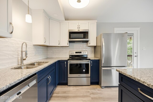 11 White Ln, Oak Island, NC 28465 - kitchen with stainless steel appliances, blue cabinetry, white cabinetry, light stone counters, and lofted ceiling