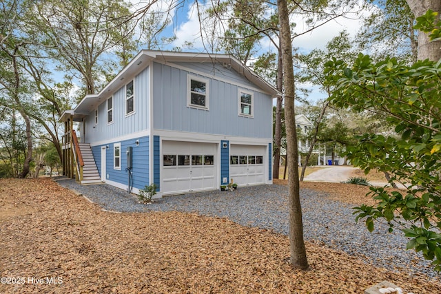 view of side of property with a garage, board and batten siding, driveway, and stairs
