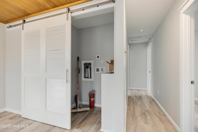 hall with a barn door and light wood-type flooring