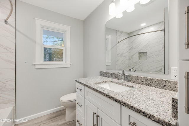 full bathroom with vanity, tiled shower / bath, hardwood / wood-style floors, and toilet