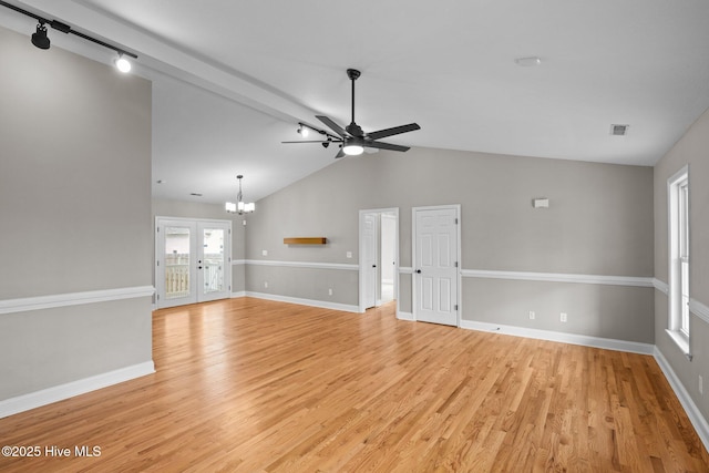 unfurnished living room with light wood-type flooring, ceiling fan with notable chandelier, vaulted ceiling with beams, and track lighting