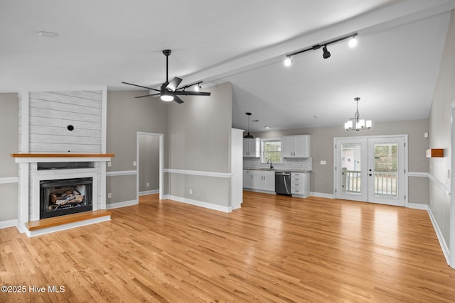 unfurnished living room with a fireplace, sink, light wood-type flooring, track lighting, and lofted ceiling with beams