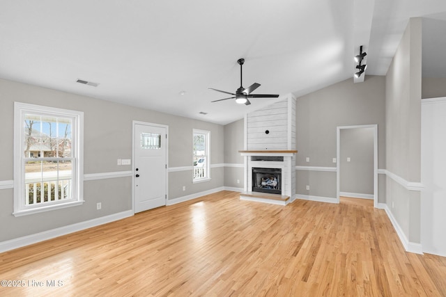 unfurnished living room featuring a large fireplace, vaulted ceiling, ceiling fan, and light hardwood / wood-style flooring