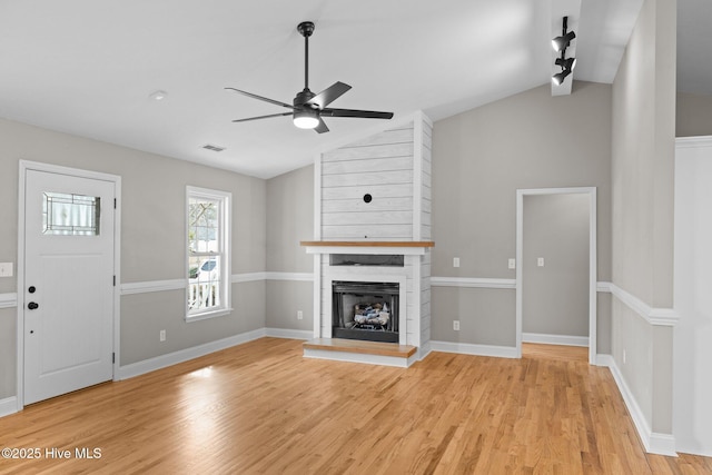 unfurnished living room featuring light hardwood / wood-style floors, a large fireplace, lofted ceiling, and ceiling fan