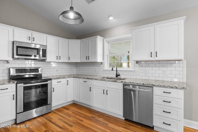 kitchen featuring sink, stainless steel appliances, white cabinets, and pendant lighting