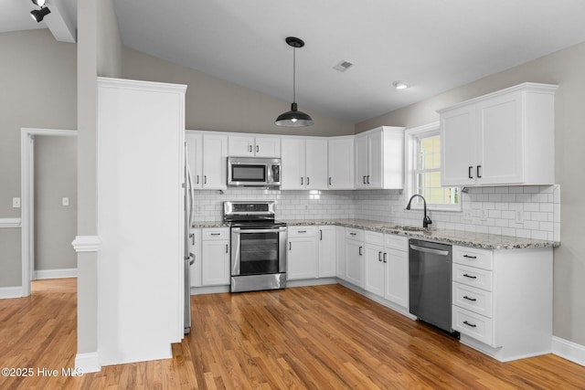 kitchen with white cabinets, decorative light fixtures, stainless steel appliances, tasteful backsplash, and sink