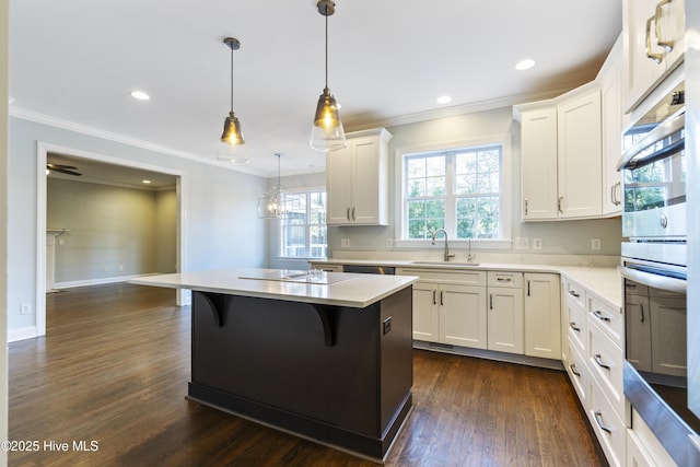 kitchen featuring sink, a breakfast bar, white cabinetry, hanging light fixtures, and a kitchen island