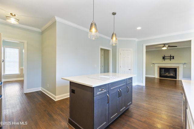 kitchen with crown molding, a tile fireplace, a kitchen island, dark hardwood / wood-style flooring, and decorative light fixtures