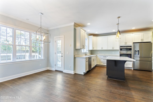 kitchen featuring crown molding, a center island, hanging light fixtures, dark hardwood / wood-style flooring, and stainless steel appliances