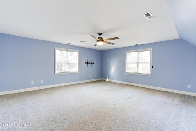 carpeted empty room with ceiling fan, a healthy amount of sunlight, and vaulted ceiling