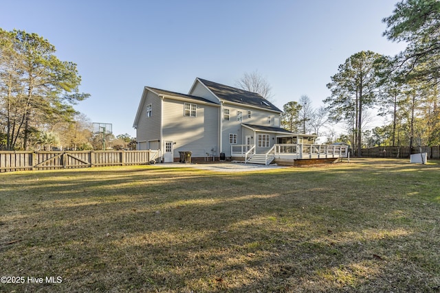 rear view of property featuring a lawn, a sunroom, and a deck