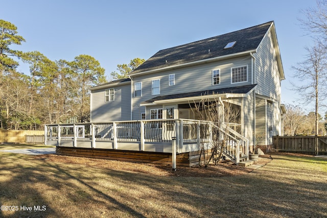 rear view of property with a lawn, a sunroom, and a deck