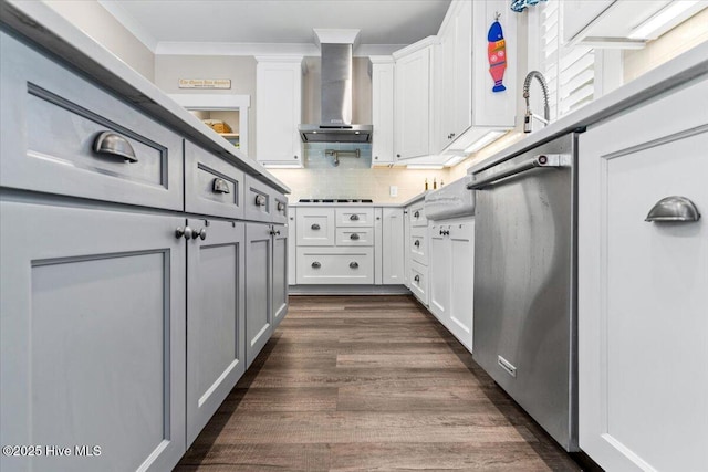 kitchen featuring white cabinets, ornamental molding, dark wood-style flooring, wall chimney range hood, and backsplash