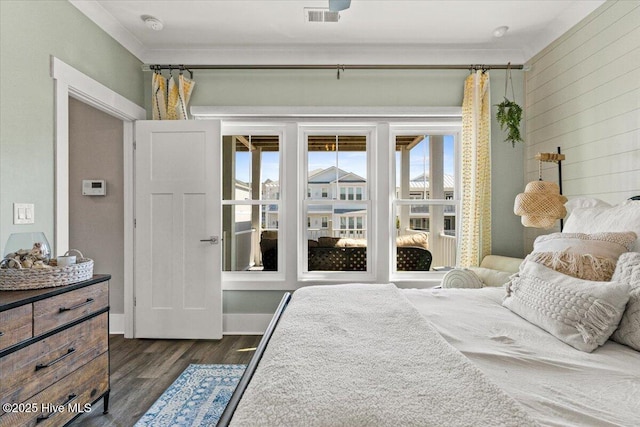 bedroom with ornamental molding, wood walls, dark wood-style flooring, and visible vents