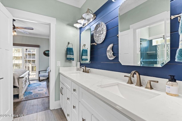 ensuite bathroom with double vanity, wood finished floors, a sink, and connected bathroom