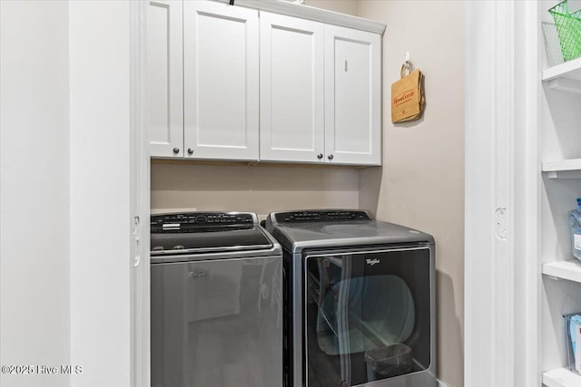 clothes washing area featuring separate washer and dryer and cabinet space