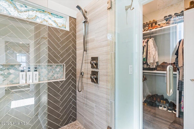 bathroom featuring a shower stall and a spacious closet