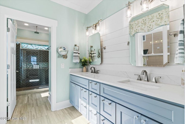 bathroom with double vanity, a stall shower, baseboards, and a sink