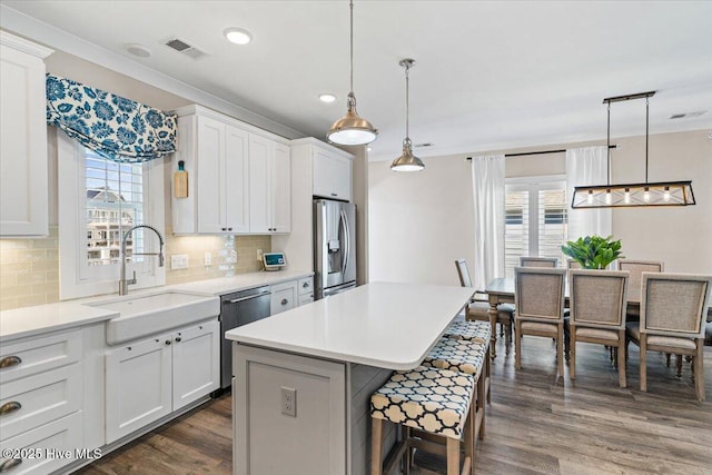 kitchen with stainless steel appliances, dark wood-style flooring, a sink, and a kitchen bar