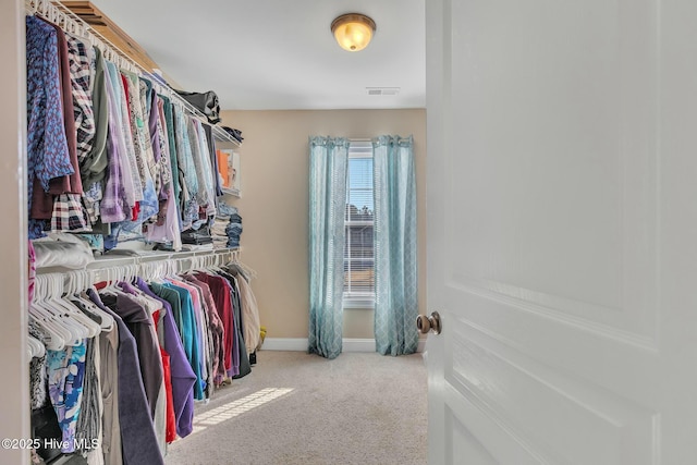 walk in closet featuring light colored carpet