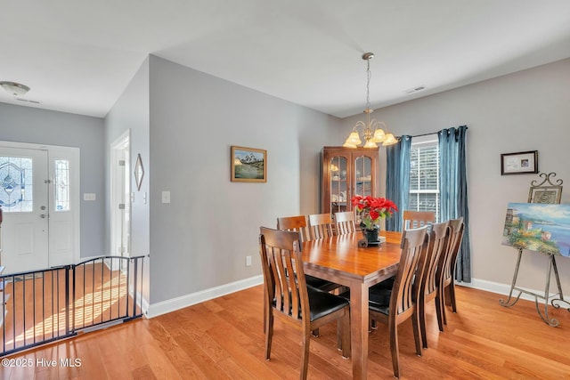 dining area with light wood-type flooring and a chandelier