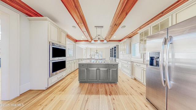 kitchen with gray cabinets, a kitchen island, pendant lighting, beamed ceiling, and stainless steel appliances