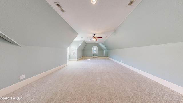 bonus room featuring lofted ceiling, ceiling fan, carpet, and a textured ceiling