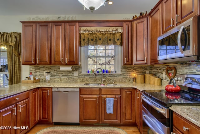 kitchen with appliances with stainless steel finishes, light stone counters, tasteful backsplash, and sink