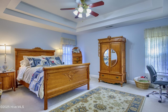 bedroom featuring ceiling fan, light carpet, and a raised ceiling