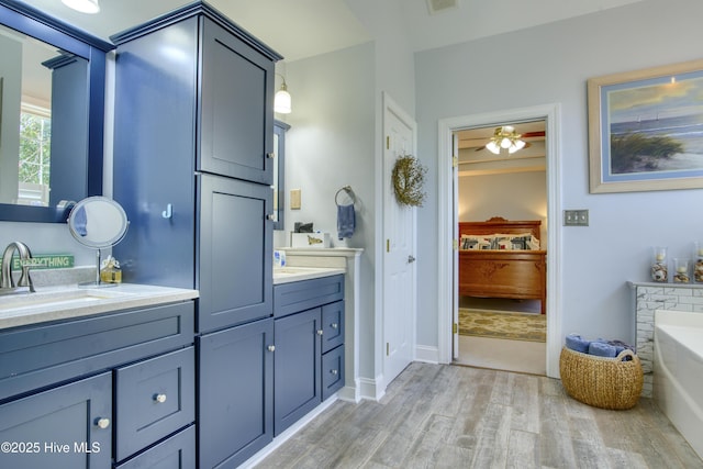 bathroom with ceiling fan, a tub to relax in, hardwood / wood-style flooring, and vanity