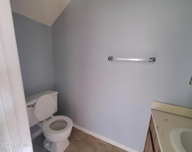 bathroom with toilet, lofted ceiling, tile patterned floors, and vanity