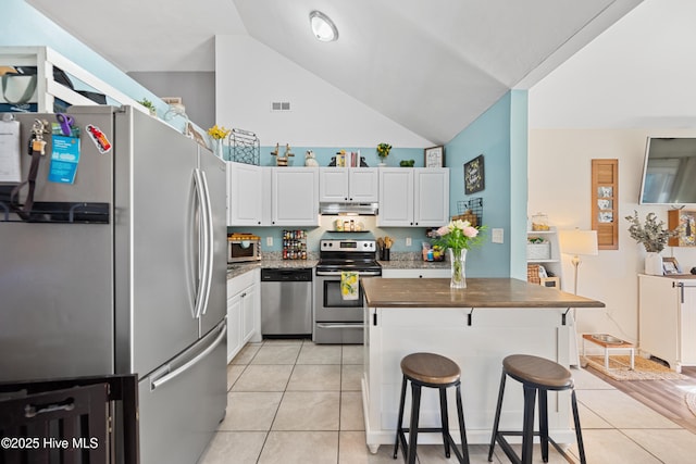 kitchen featuring white cabinetry, light tile patterned floors, stainless steel appliances, and a kitchen breakfast bar