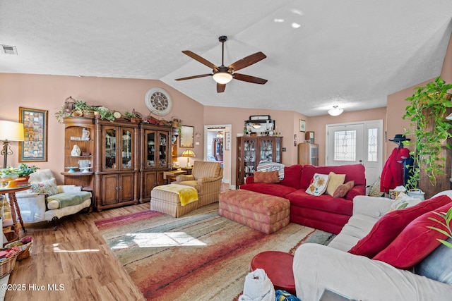 living room with vaulted ceiling, hardwood / wood-style floors, ceiling fan, and a textured ceiling