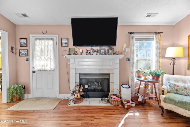 living room featuring hardwood / wood-style flooring, a tile fireplace, and a textured ceiling