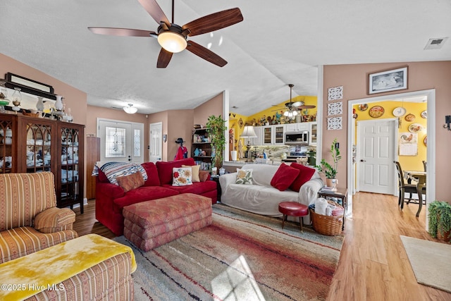 living room featuring ceiling fan, lofted ceiling, and light wood-type flooring