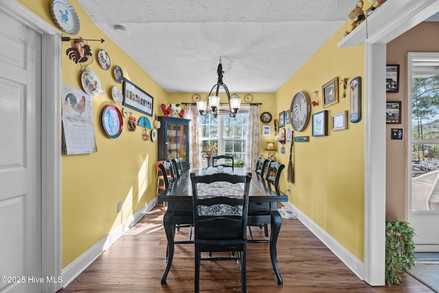 dining space featuring an inviting chandelier, wood-type flooring, and a textured ceiling