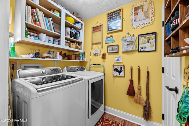 laundry room with washing machine and clothes dryer, wood-type flooring, and a textured ceiling