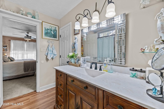 bathroom with hardwood / wood-style flooring, vanity, ceiling fan, and a textured ceiling