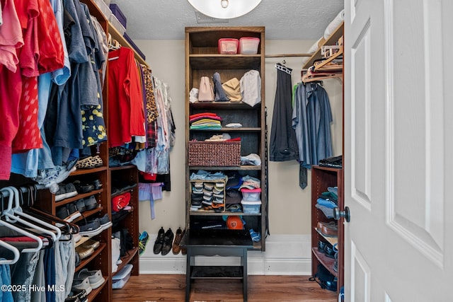 walk in closet with dark hardwood / wood-style flooring