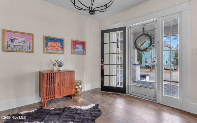 foyer entrance featuring ceiling fan with notable chandelier, hardwood / wood-style flooring, french doors, and a fireplace