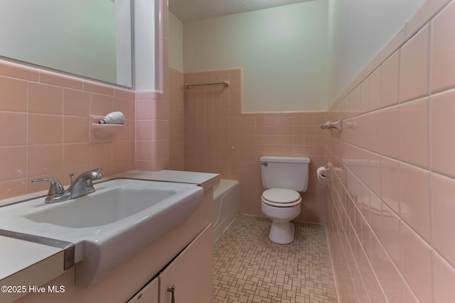 bathroom with tile patterned floors, tile walls, toilet, and vanity