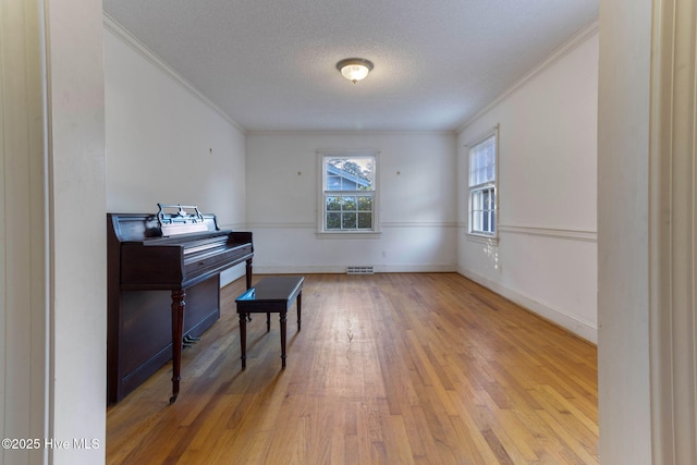 miscellaneous room featuring a textured ceiling, crown molding, and light wood-type flooring