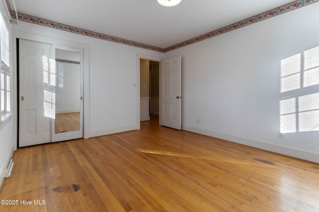 empty room featuring a textured ceiling, a healthy amount of sunlight, and light hardwood / wood-style flooring