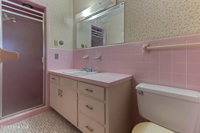 bathroom featuring a shower with shower door, vanity, tile walls, and toilet