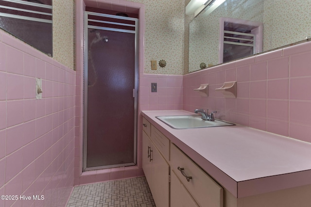 bathroom featuring a shower with shower door, tile walls, tile patterned floors, and vanity