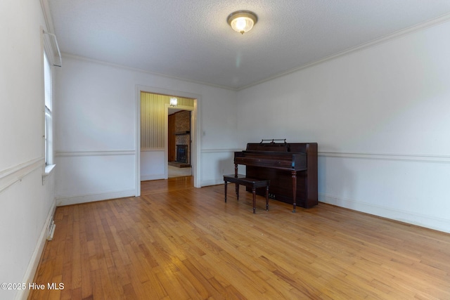 misc room with light wood-type flooring, crown molding, and a textured ceiling