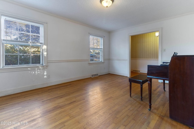 office space with hardwood / wood-style flooring, baseboard heating, a textured ceiling, and ornamental molding